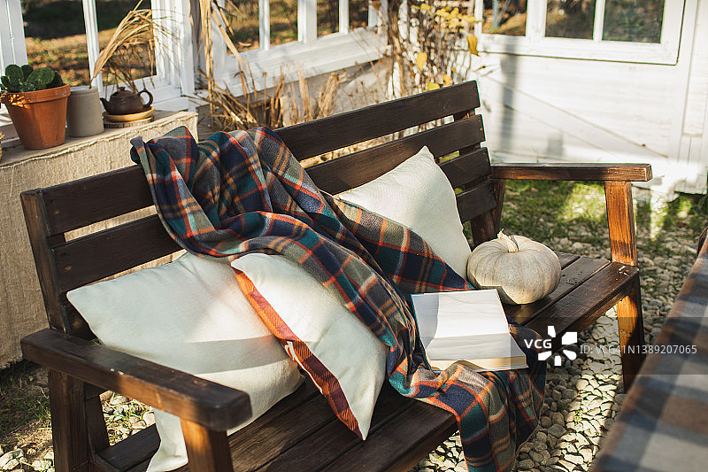 舒适的家庭露台，木制长凳上放着枕头、羊毛毯和书图片素材