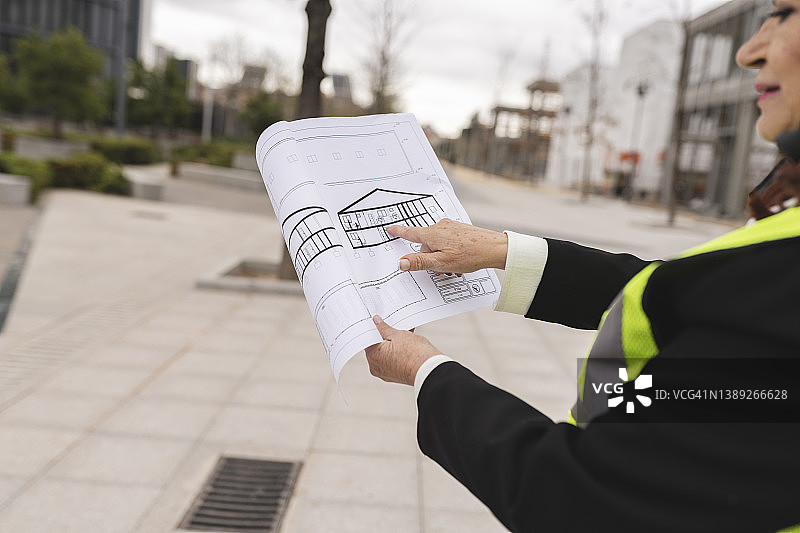 女建筑师的手指向建筑工地房屋的平面图图片素材