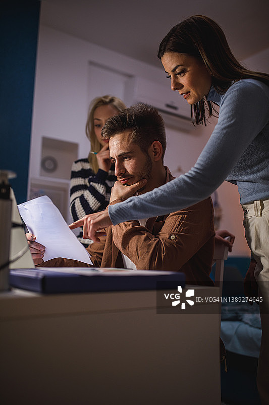 两名年轻女子帮助她们的男性室友赶工作进度图片素材