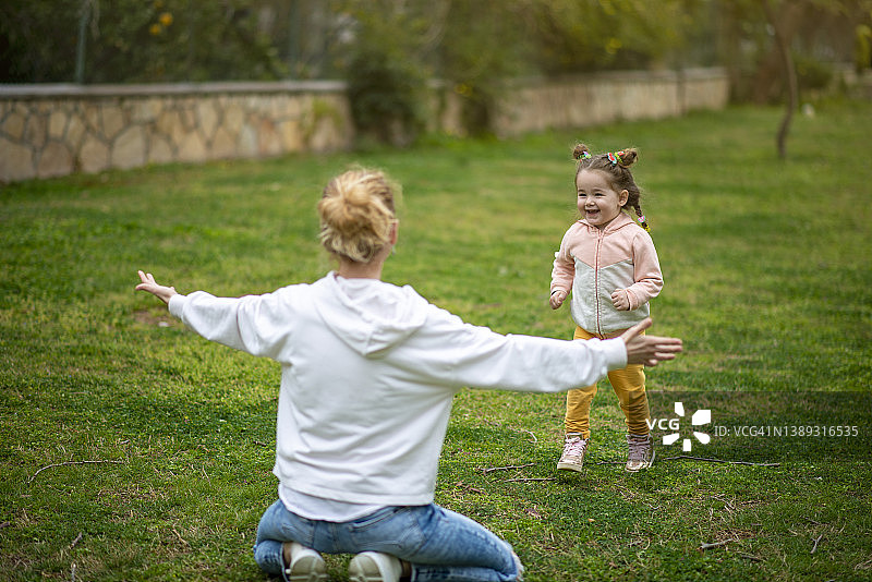 快乐的女宝宝跑进妈妈的怀里图片素材