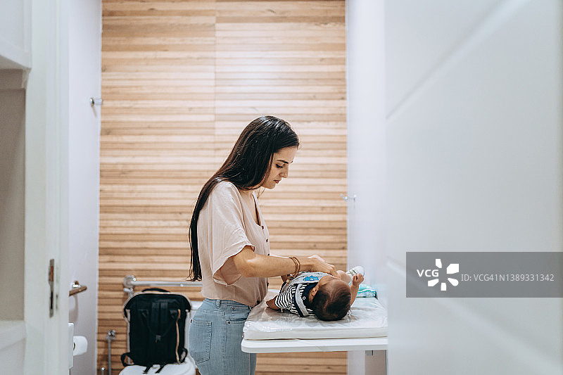 母亲在更换台上给宝宝换尿布图片素材