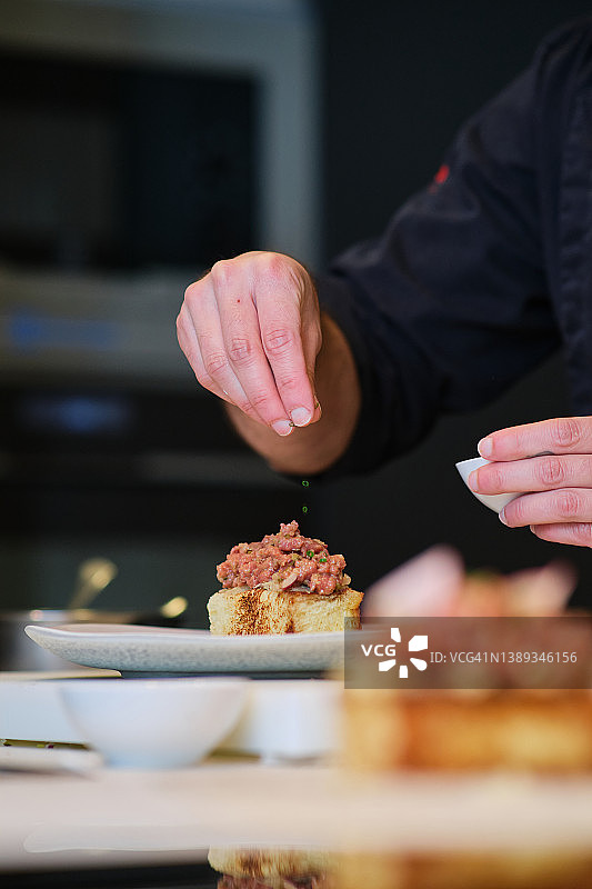 厨师在盘子上为鞑靼牛排调味图片素材