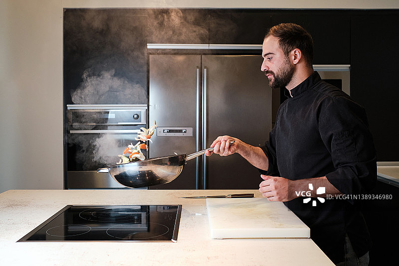 厨师在现代厨房的平底锅中烹饪蔬菜图片素材