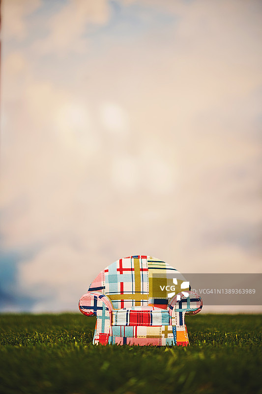 多云天空下草地上的可爱拼布沙发图片素材