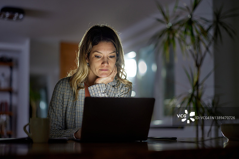 在家办公室内深夜用电脑工作的年轻女商人图片素材