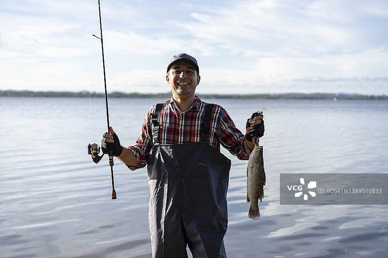自豪的渔民在河里拿着鱼图片素材