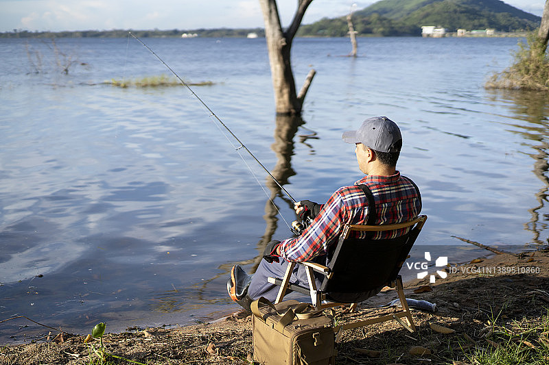 男人在湖边钓鱼。图片素材