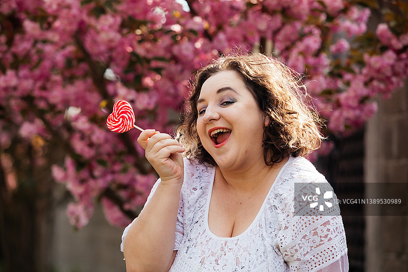 拿着棒棒糖的身体积极女性的有趣肖像图片素材