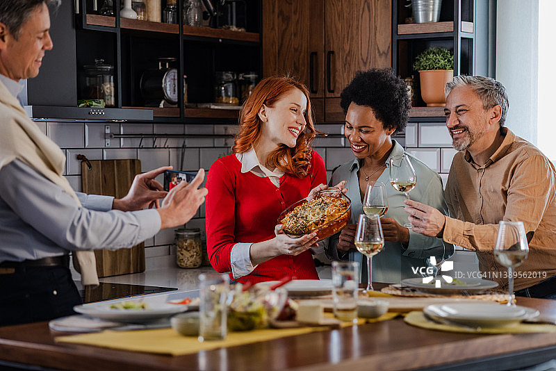 男人和朋友共进晚餐时用智能手机记录美好回忆图片素材