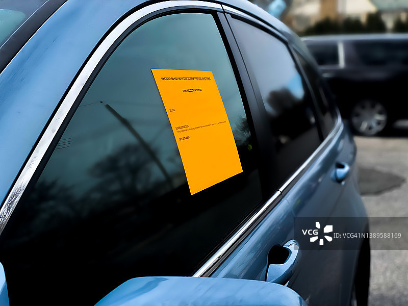 车轮锁：停放车辆上的亮橙色固定通知贴纸图片素材