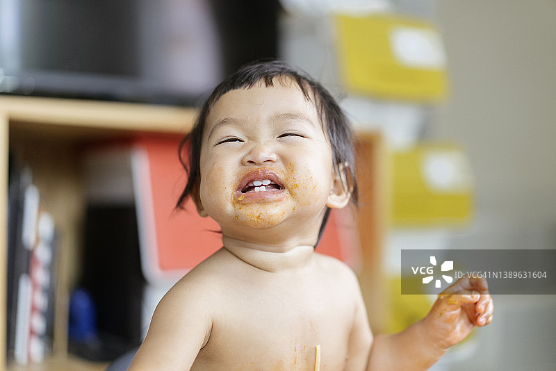 快乐的亚洲女宝宝在家用叉子吃面条图片素材