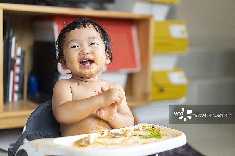 快乐的亚洲女宝宝在家用叉子吃面条图片素材