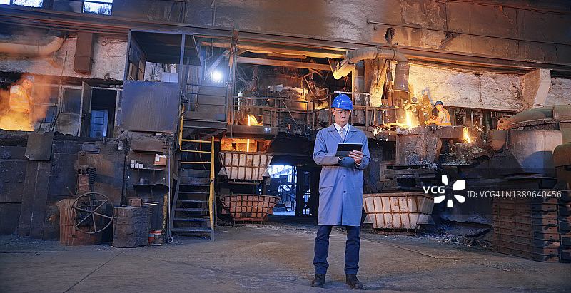 男人工程师在铸造厂使用数字平板电脑图片素材