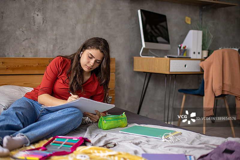 一边听音乐一边在素描本上绘画的少女图片素材