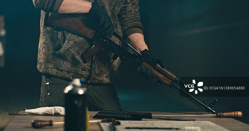 男人清洁AK-47步枪，拆卸并准备使用图片素材