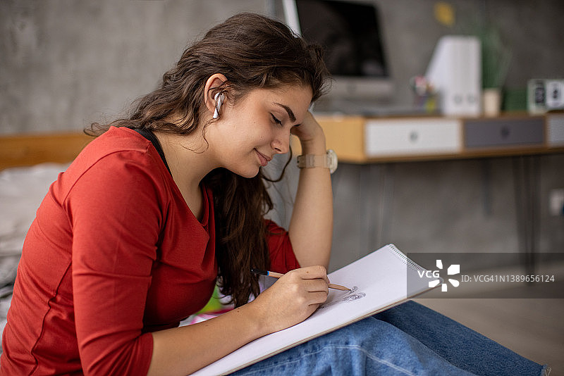 一边听音乐一边在素描本上绘画的少女图片素材