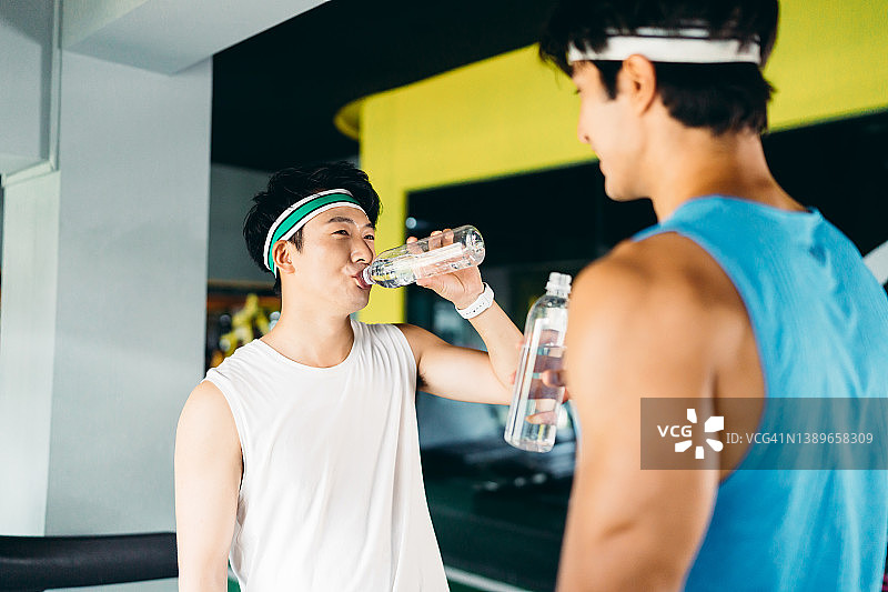 在健身房训练后喝水的健壮男人，健康和健身理念图片素材