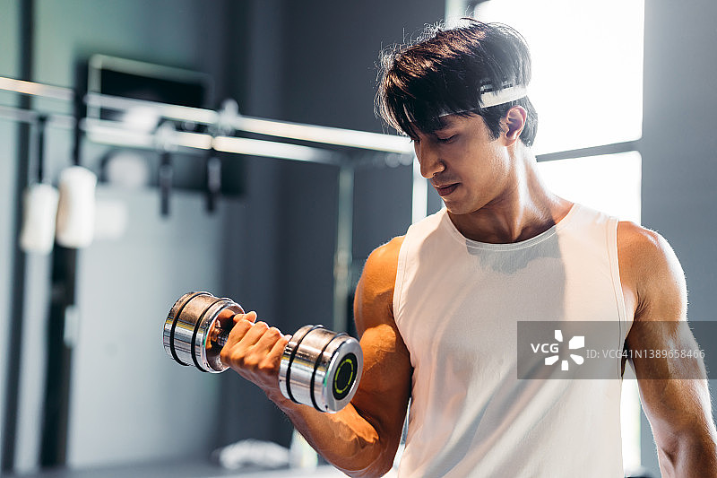 运动型男人在健身房举重，健康与健身概念图片素材