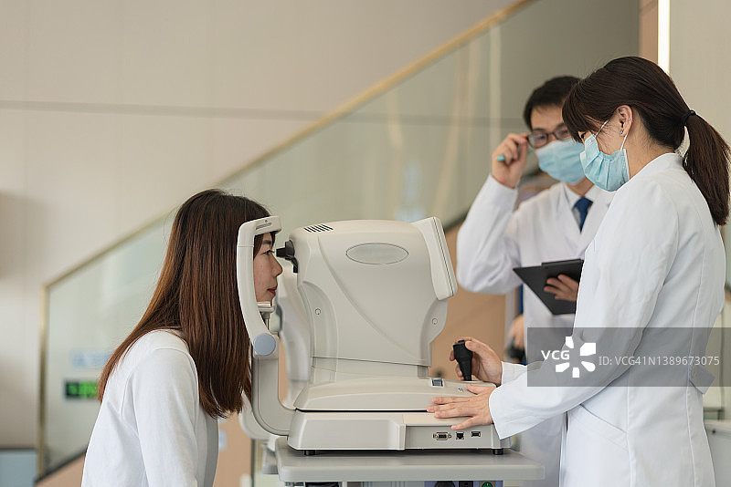 眼科医生和护士使用现代仪器检查女病人的眼睛图片素材