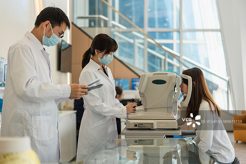 眼科医生和护士使用现代仪器检查女病人的眼睛图片素材