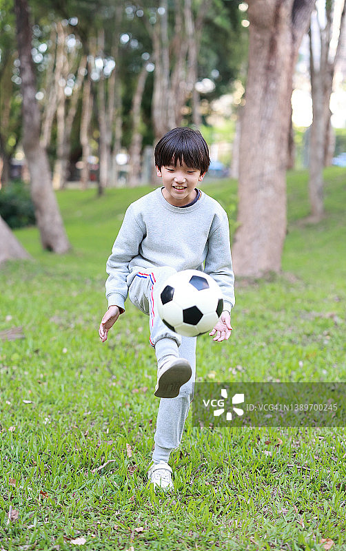 小男孩在公园里踢足球图片素材