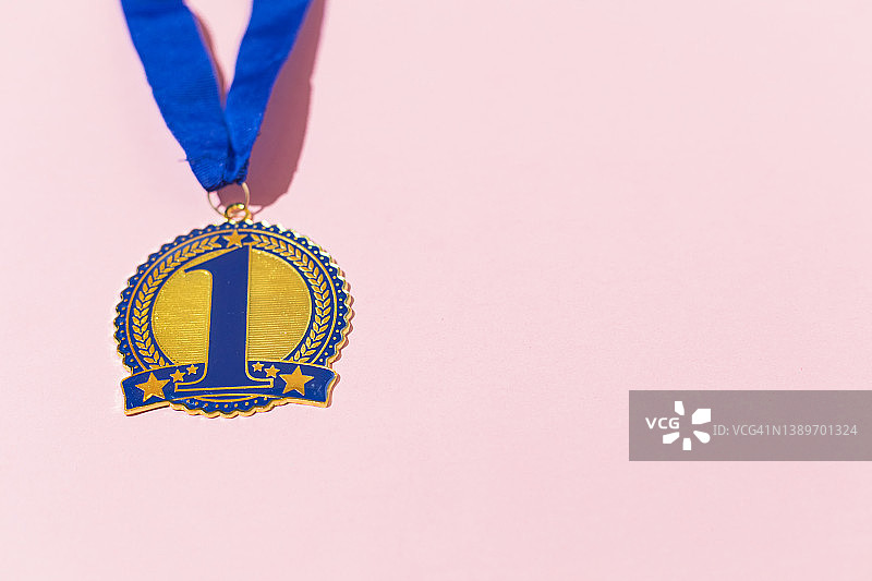 蓝色第一名奖牌，粉色背景上的竞赛获胜概念图片素材