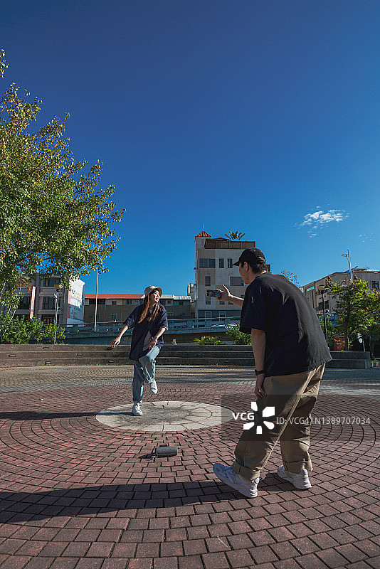 亚洲，台湾，两个年轻人在公园里跳舞和拍摄。图片素材