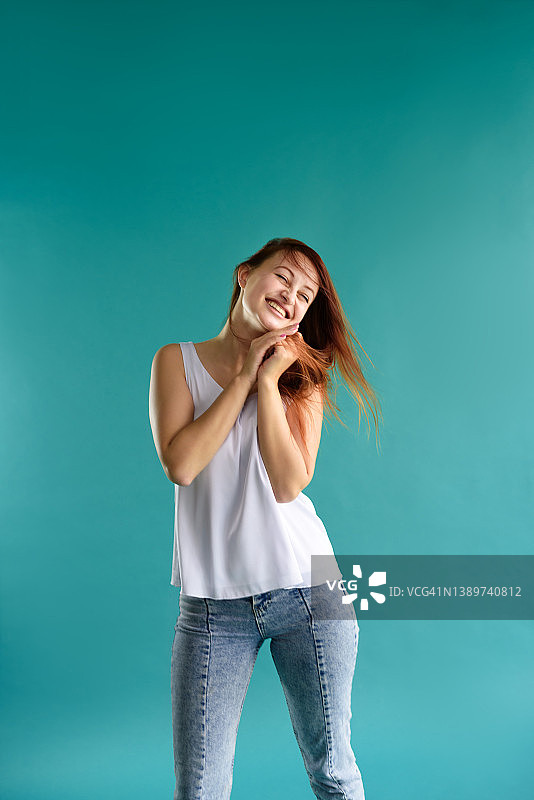 蓝底滑稽表情的快乐红发年轻女子特写图片素材