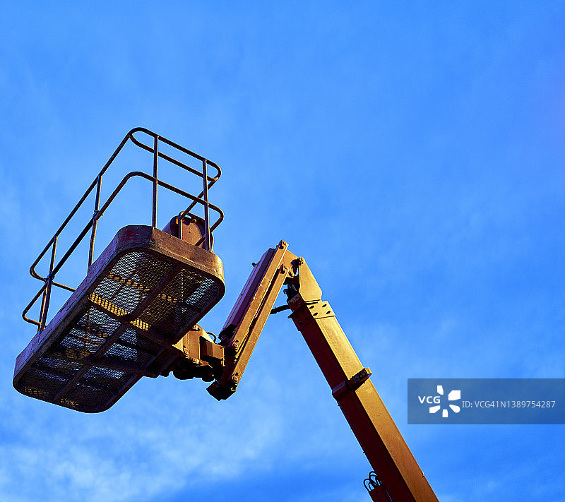 建筑区域的蓝色天空背景下的黄色起重机吊篮图片素材