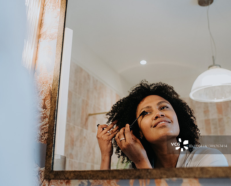 一位微笑的女士在浴室镜子里涂睫毛膏图片素材