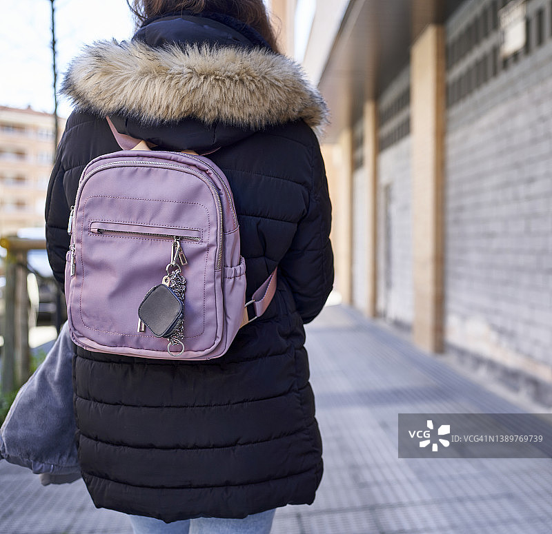 寒冷清晨，身穿冬装的女人走在金融区的人行道上图片素材