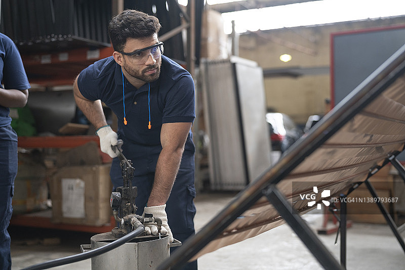 工人在太阳能电池板工厂向面板注水进行测试图片素材