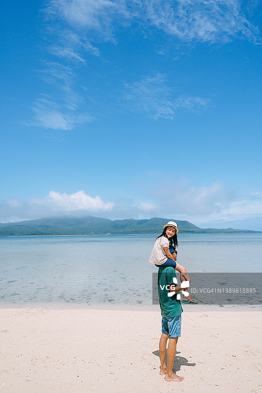 父亲在海滩上肩扛小女儿图片素材