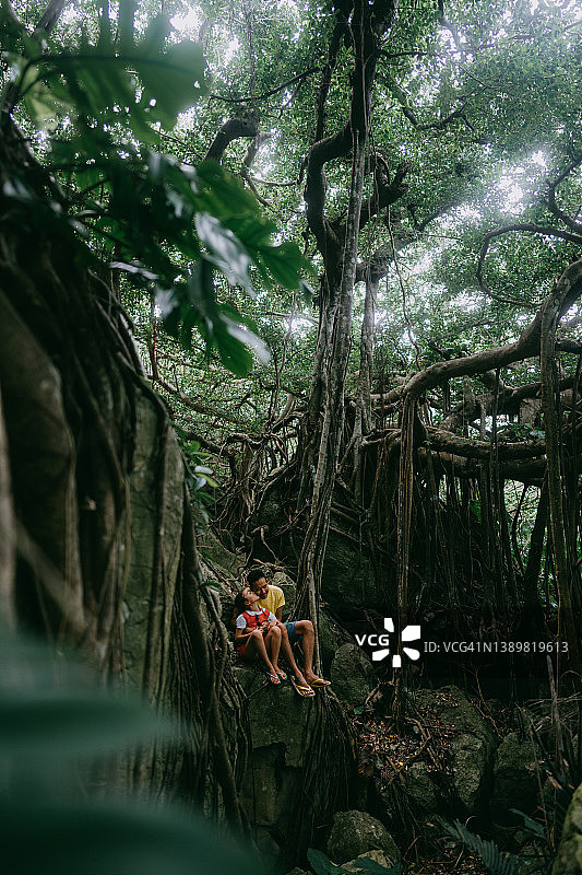 父亲和孩子在冲绳的丛林中与榕树，中国日本图片素材