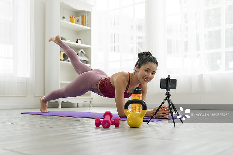 美丽女人在家练习，用手机在线观看课程肖像图片素材