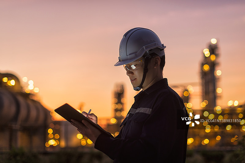 炼油厂夜班工程师用平板电脑进行轮班前检查图片素材
