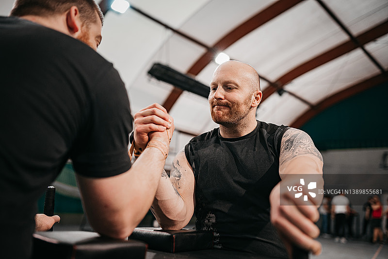 两位健壮的年轻男人在健身房里扳手腕图片素材