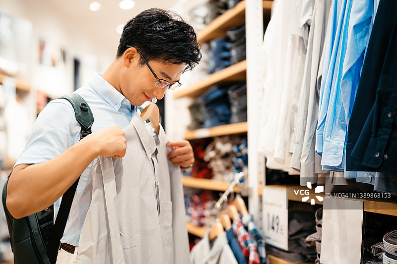 在服装店挑选新衣服的年轻亚洲男人图片素材