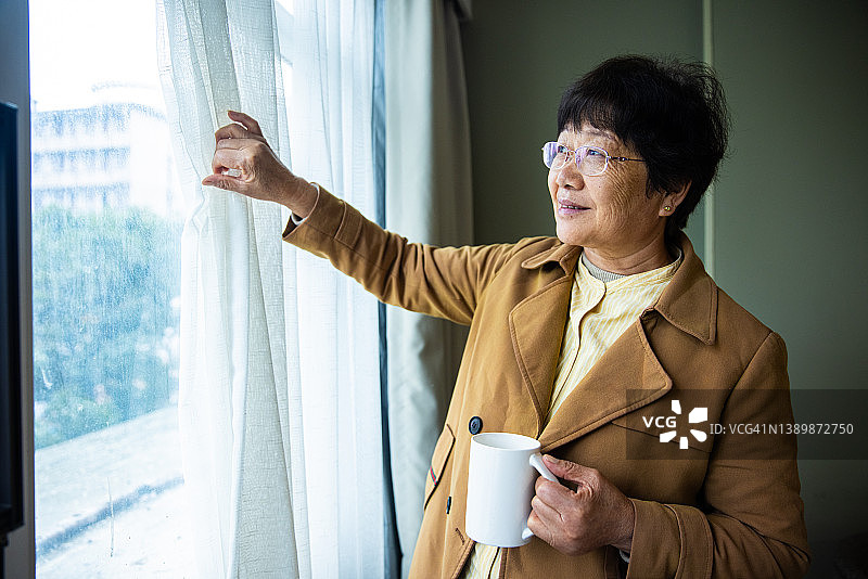 年长的女性在家打开窗帘图片素材