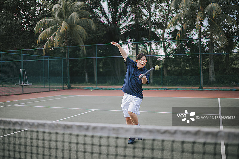 在网球场练习的唐氏综合征中国男网球运动员图片素材