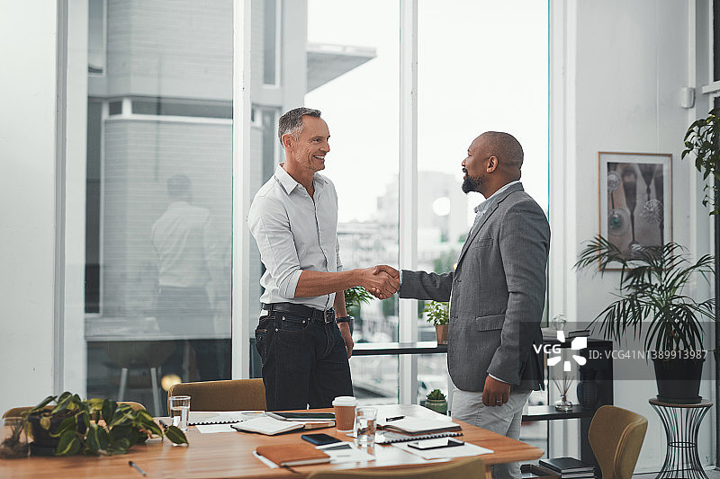 现代办公室里两位成熟的商人握手的镜头图片素材