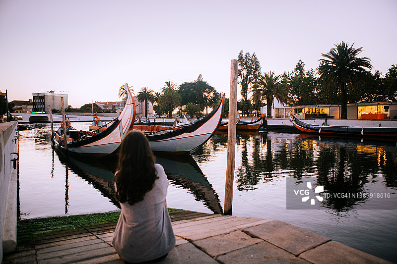 游客坐在葡萄牙阿威罗观看美丽日落的后视图图片素材