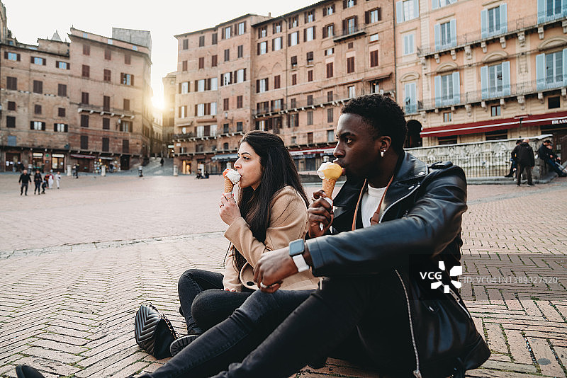 年轻夫妇在锡耶纳日落时分吃冰淇淋图片素材