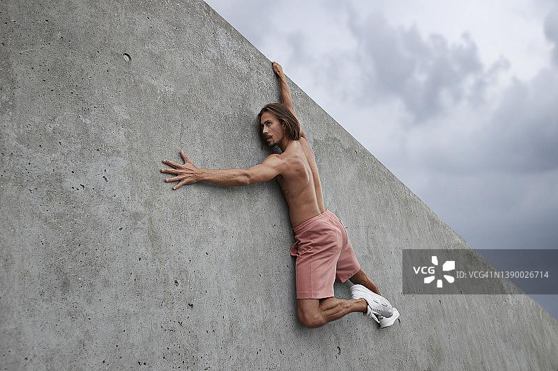 没穿上衣的男舞者悬挂在灰色墙壁上图片素材