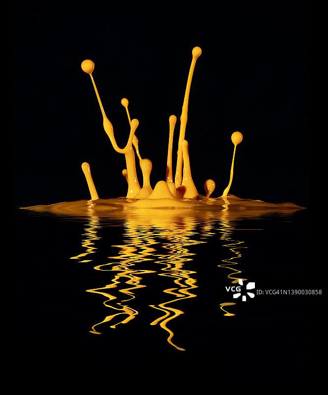 黑色背景上，水面反射的橙色油漆飞溅图片素材