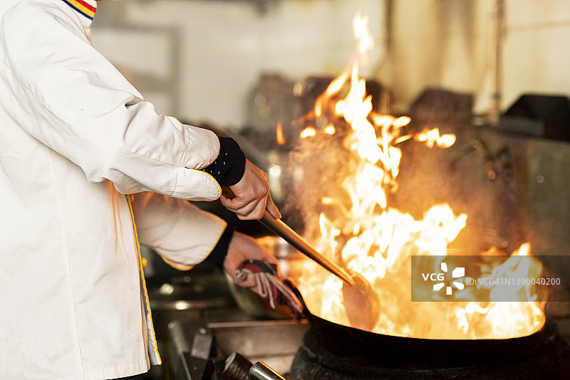 厨师在厨房炉灶的煎锅中用火焰烹饪图片素材