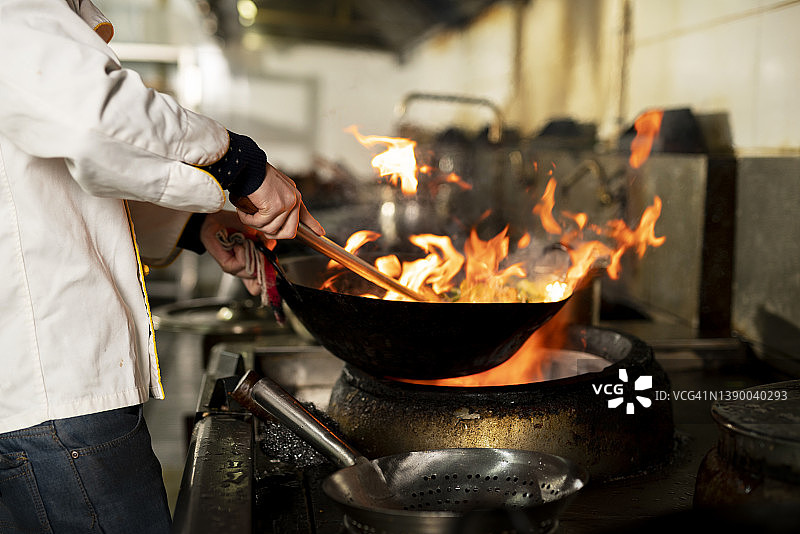 厨师在厨房炉灶的煎锅中用火焰烹饪图片素材