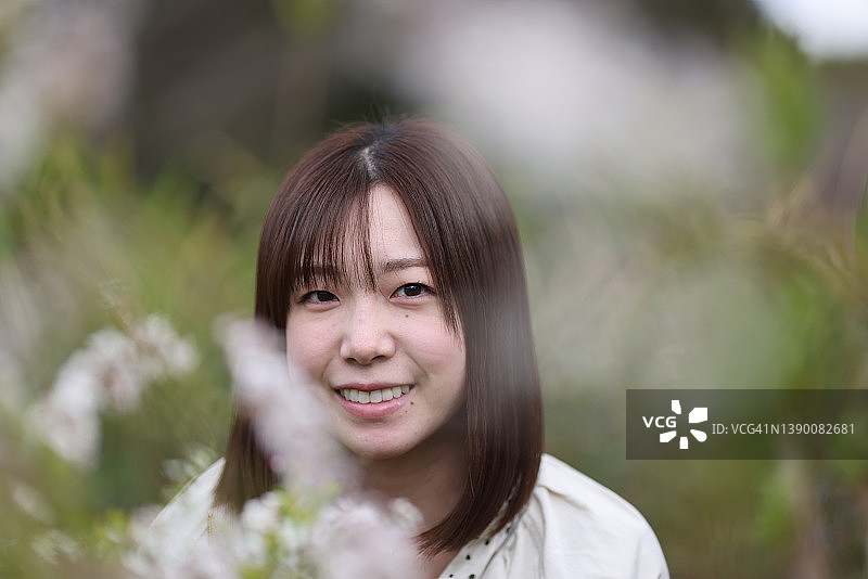 年轻女子欣赏春天的花朵图片素材
