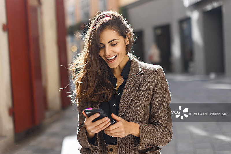 穿着棕色外套的年轻模特在看手机图片素材