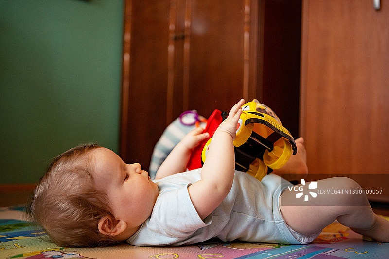 女婴躺在地板上抱着玩具图片素材